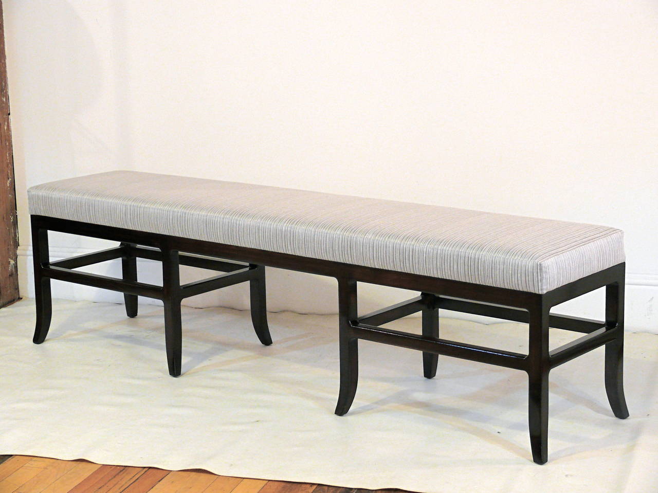Elegant Mid-Century bench in the manner of James Mont with eight sculpted splayed legs and beautiful base stretchers, refinished in a high gloss espresso and upholstered in a Robert Allen silver grey tucked fabric.