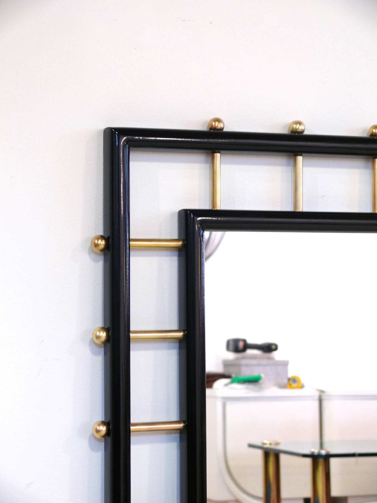 Spectacular Mid-Century Modern rectangular mirror. Multiple brass rods inserted around the middle framed mirror holding the outer frame with makes the mirror. Newly restored. Refinished in an ebonized color with a high gloss sheen. This mirror is