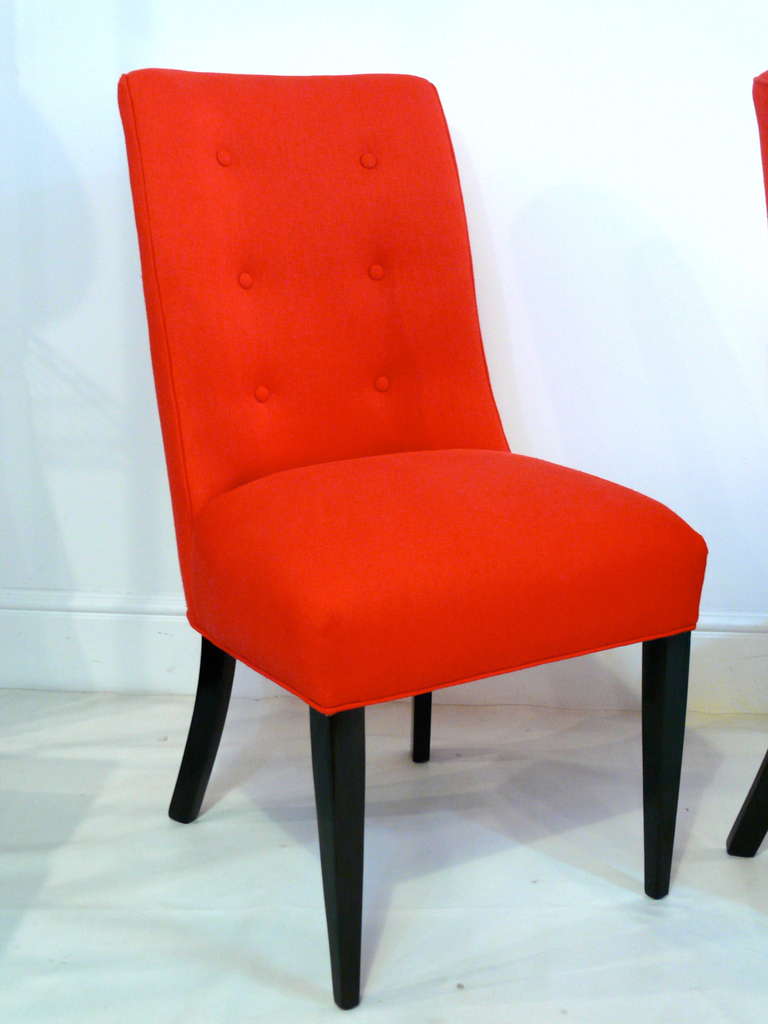 Set of four midcentury button back chairs with splayed back legs. Chairs are newly covered in poppy red cotton with ebonized legs.
