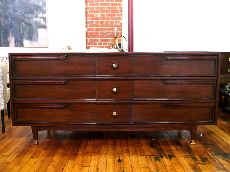 Amazing dresser by American of Martinsville refinished to perfection in a Natural Walnut with beautiful grain.  Plenty of storage with 9 drawers available and brass accents on its pulls and legs.