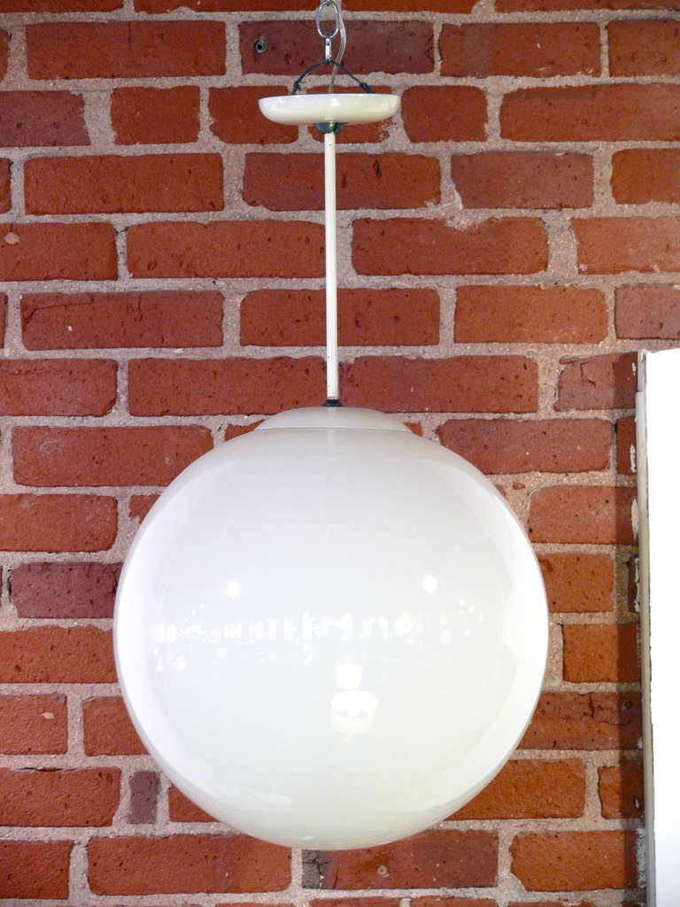 Pair of oversized white glass globe pendant lights by Kurt Versen.  The globes are hung from a metal stem with an inner 40-100 watts single socket.
