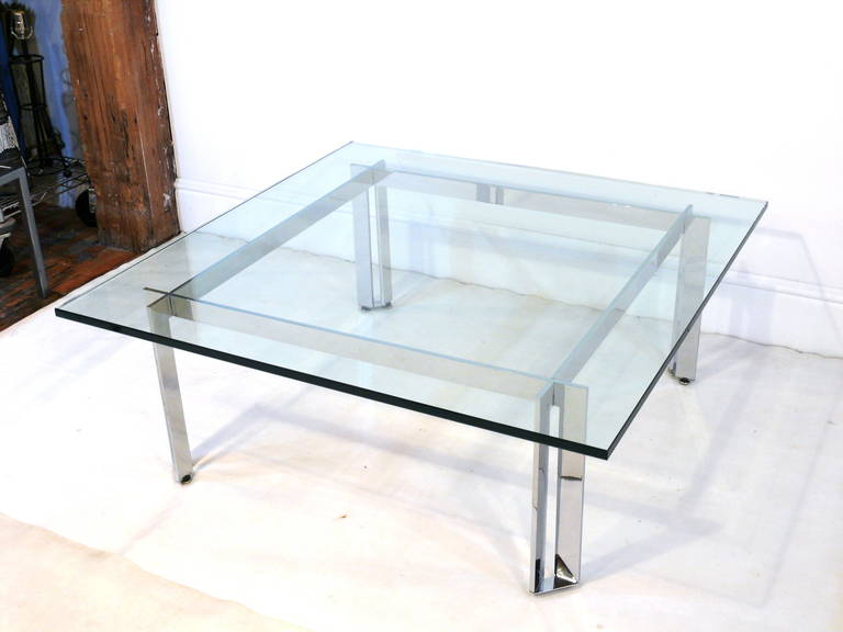 Incredible style coffee table with gleaming intersecting corner chrome beams supporting a substantial 3/4" thick glass top in the manner of Romeo Rega.
