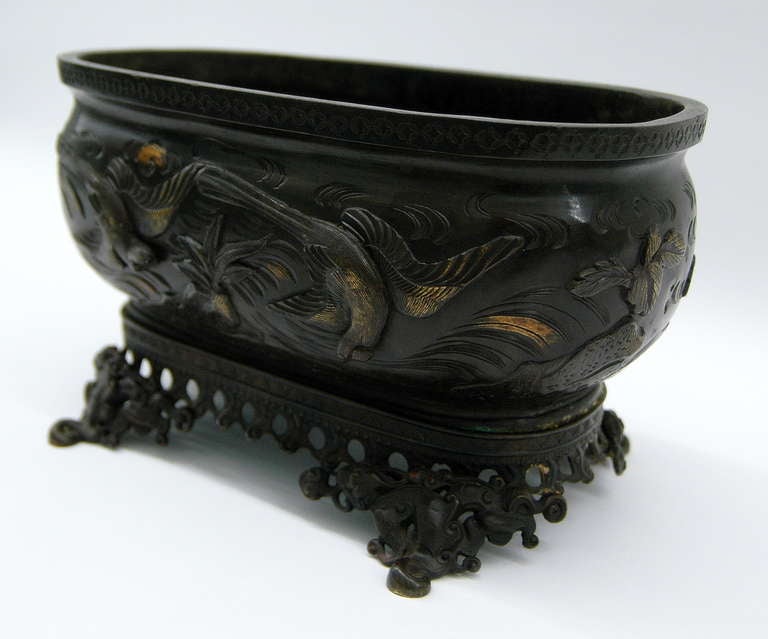 A Japanese Hibachi or jardiniere from the Meiji period casted in bronze and decorated with a phoenix in flight and organic water representations on the splayed base.