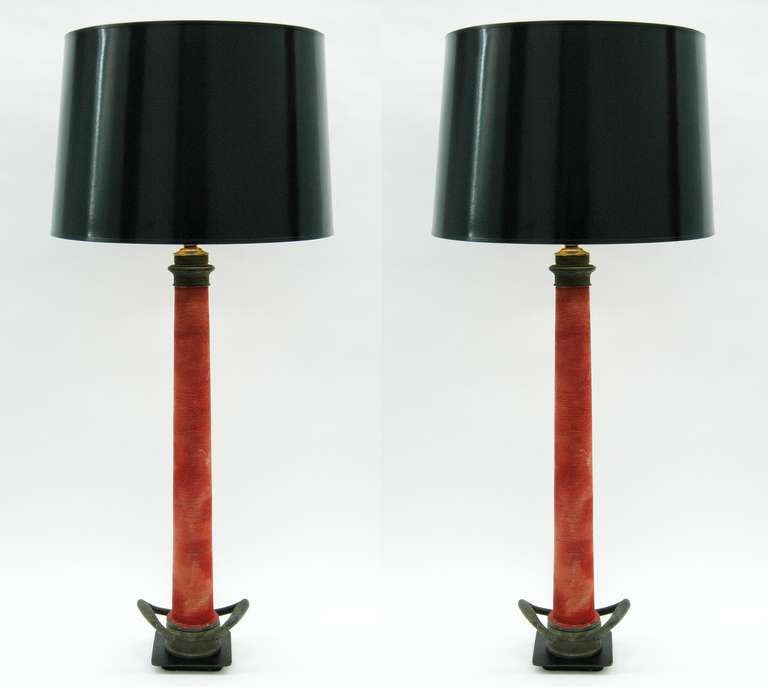 Two Large table lamps constructed from vintage fire hose nozzles on a metal base. The nozzle is made entirely out of metal and has thin red rope wrapping the entire bar. Lampshades not included.