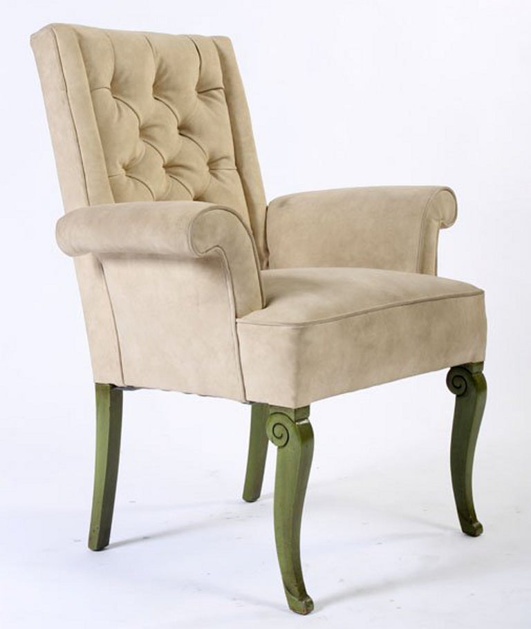 Pair upholstered armchairs based on classical Regency chair designs. Each upholstered in cream color suede with tufted back and tight seat flanked by outwardly scrolling arms. The legs of each chair finished nicely in glossy grey-green lacquer with