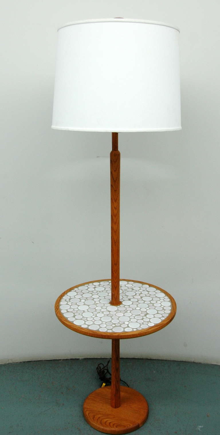 An oak floor lamp by Gordon and Jane Martz with a round small table covered in round white and light gray ceramic tiles. The lamp is signed with the Marshall Studios label and includes the original wood finial. Lampshade not included.