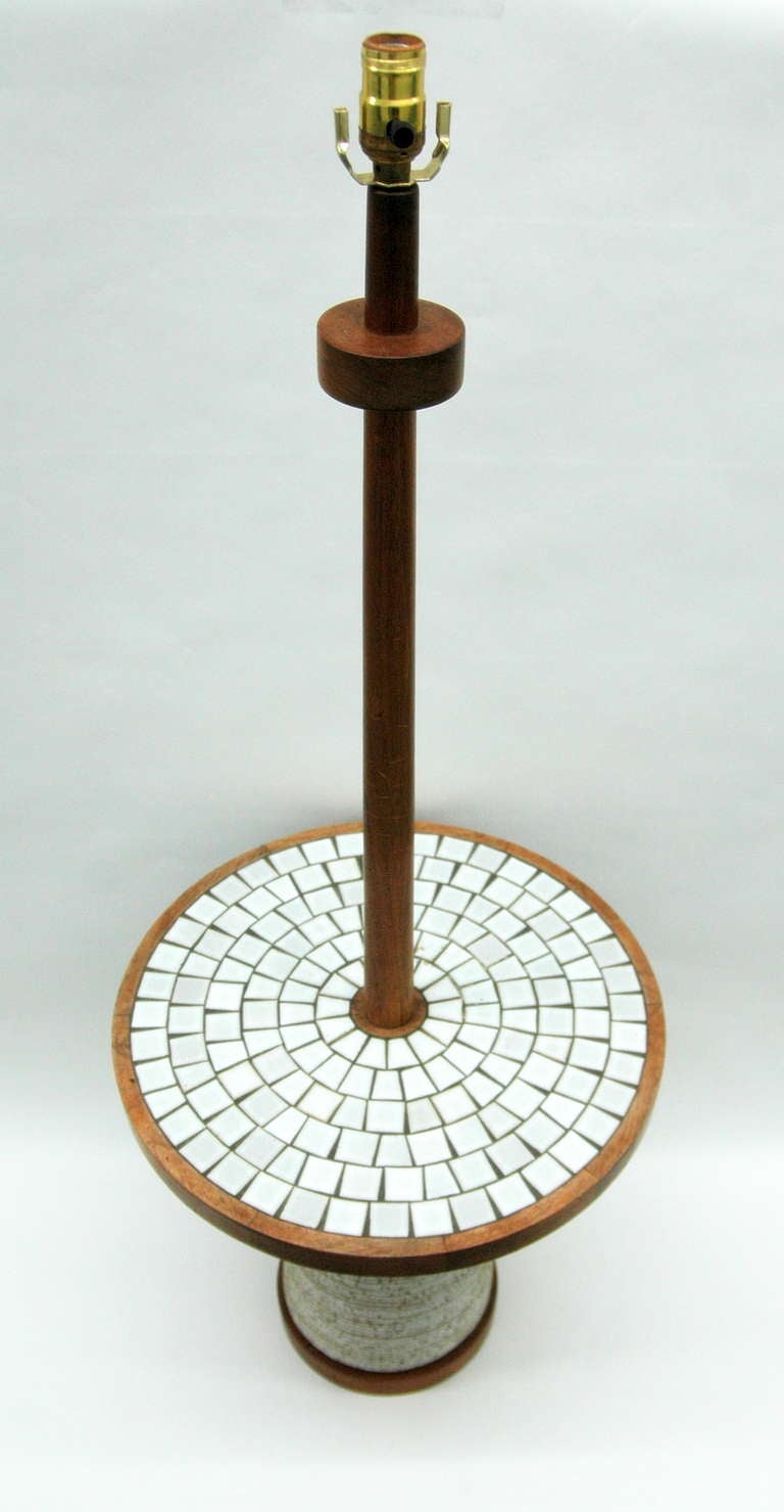 A ceramic and wood floor lamp by Gordon and Jane Martz for Marshall Studios. The lamp has an oak frame and a ceramic base with a ribbed pattern throughout. The table's surface is inlaid with white ceramic tiles that radiate from the center. The