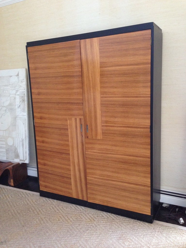 A gorgeous rosewood Art Deco cabinet with uniquely inset shagreen handles, framed by ebonized wood sides. The doors in boldly-figured rosewood arranged in contrasting vertical and horizontal sections. Opens to reveal a fully upholstered interior