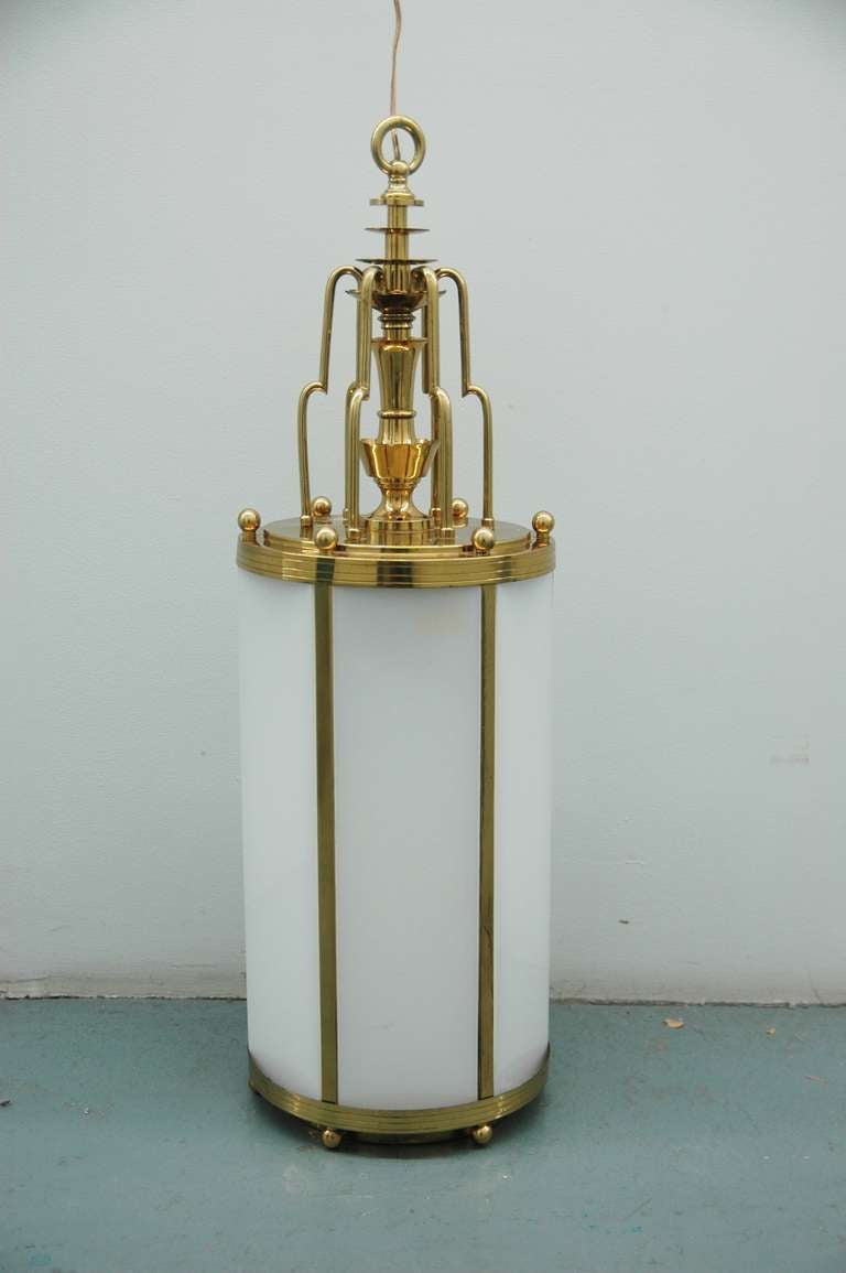 A large brass hanging lantern with streamlined design encasing frosted glass.