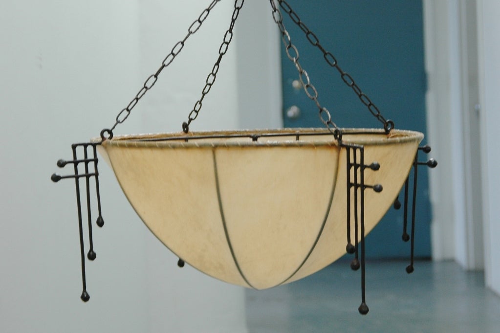 A ceiling light made of hand-wrought iron covered in parchment which conceals the bulb with four corner details in the manner of Josef Hoffmann.