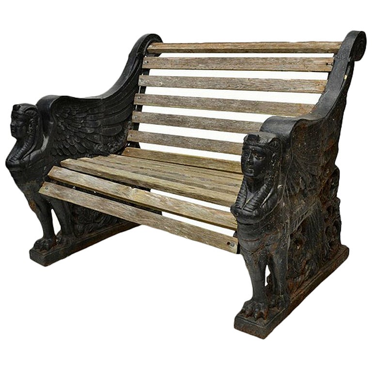 Good pair of Egyptian Revival cast iron and wood garden benches with sphinx end supports supporting slatted wood seat. 

Iron benches of this particular design are often attributed to SLB Ironworks of Sittingbourne, Kent.