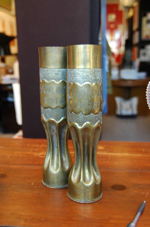 Pair of hammered and shaped brass artillery casings converted into vases. One side of each vase with a single rose, reverse with 