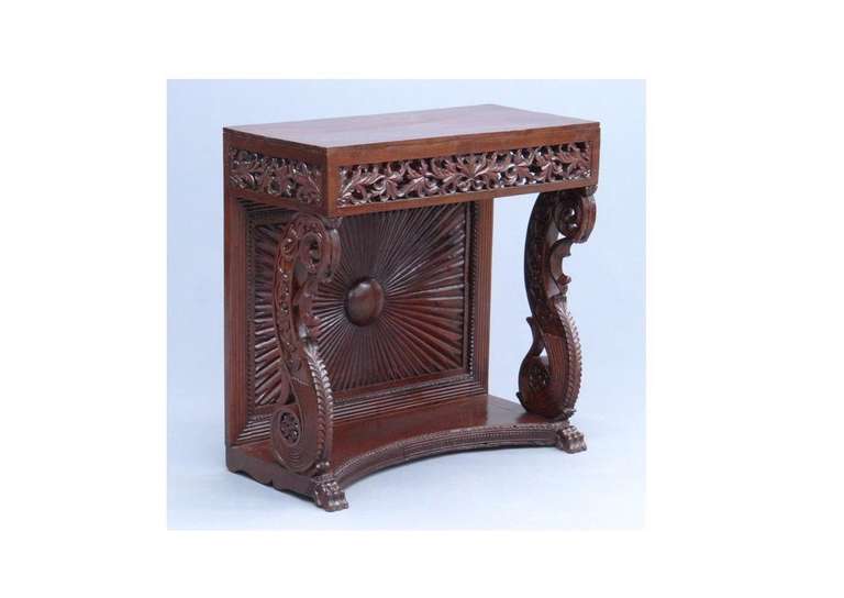 A mahogany console table with intricate carvings throughout including two lion's paws on the base and a star burst pattern on the back.