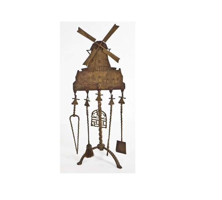 A forged bronze fireplace set with a detailed windmill with rotating blades and each tool has a windmill that resembles the stand. This piece is attributed to Oscar Bruno Bach, a German born craftsman known for his decorative metalwork during the