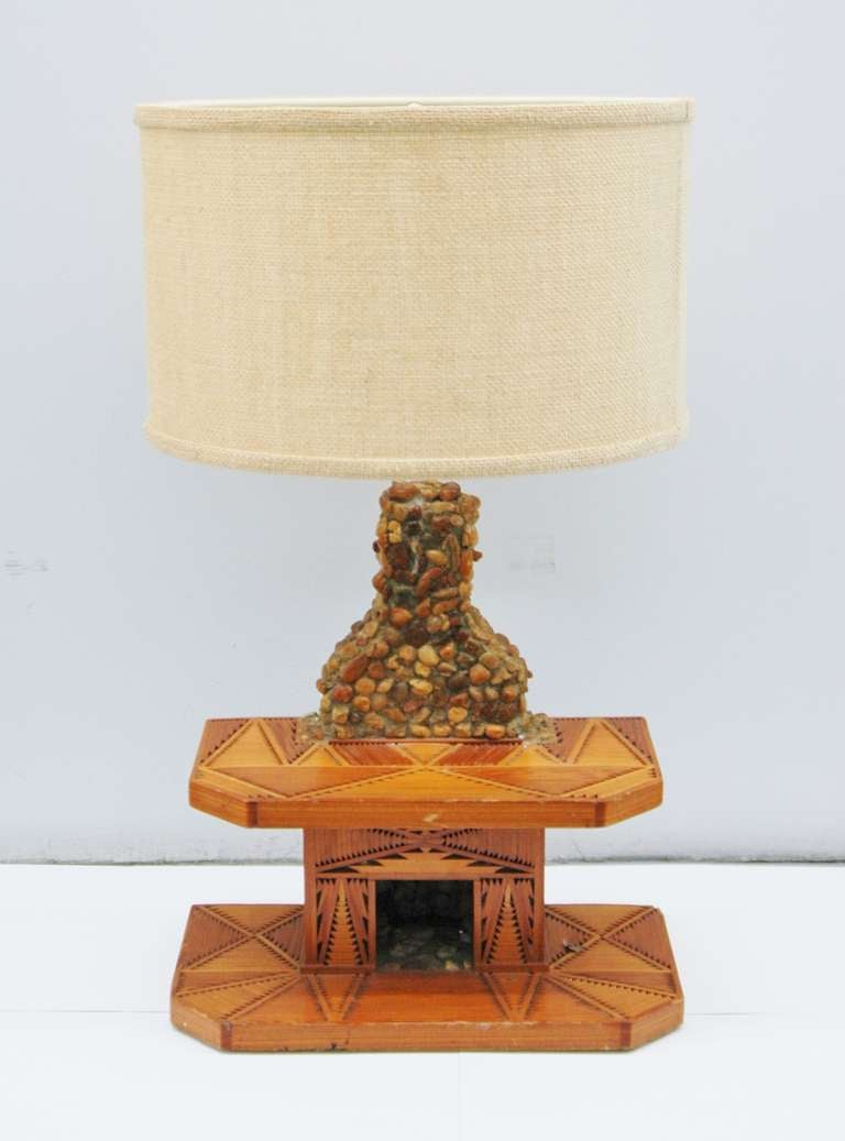 A Tramp Art table lamp in the form of a fireplace with a wood marquetry base and mantel. The Chimney holds the light socket and is covered with small stone pebbles.
Perfect for country house or ski chalet.
Rewired with French twisted silk cord.