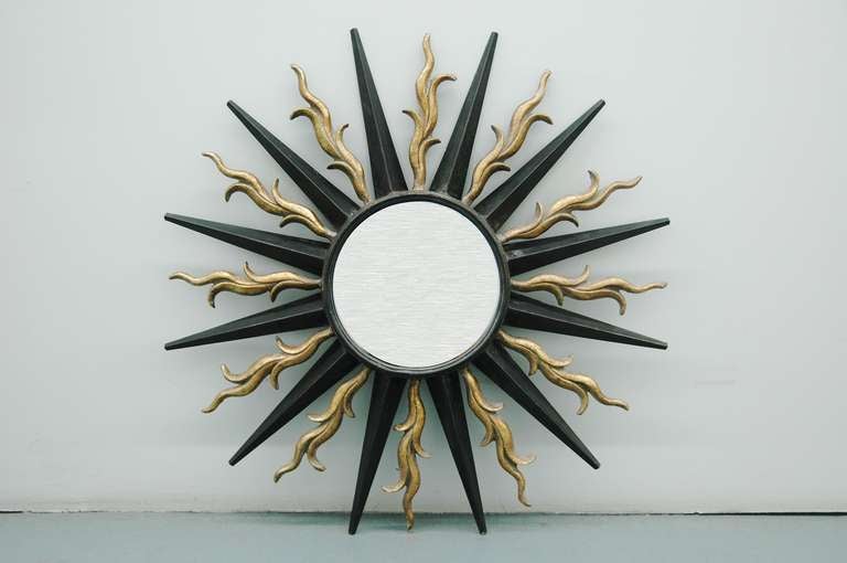 A large wall-mounted sunburst mirror in the style of Gilbert Poillerat. Poillerat was a French designer who mostly worked in wrought iron and is associated with the Art Deco period reaching into the 1930s and 1940s. He received his training at École