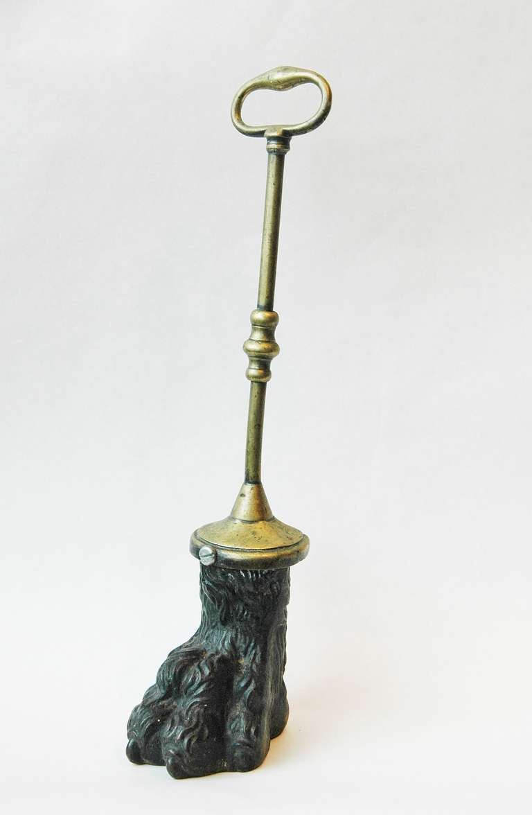 A Unique cast iron and brass door stop formed as a lions paw with a turned handle.