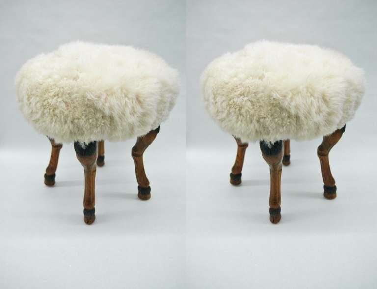 Two vintage stools with carved wooden hooved feet recently upholstered in a white shearling.