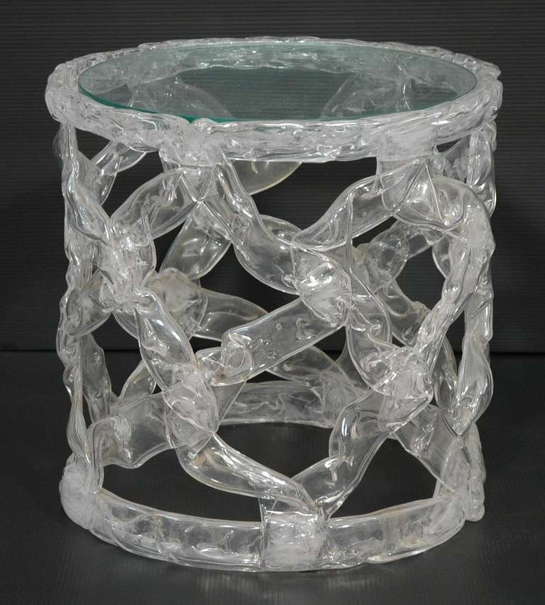 A side table by designer Tony Duquette made of transparant plastic in a pulled Taffy design. The clear base has a round glass insert.