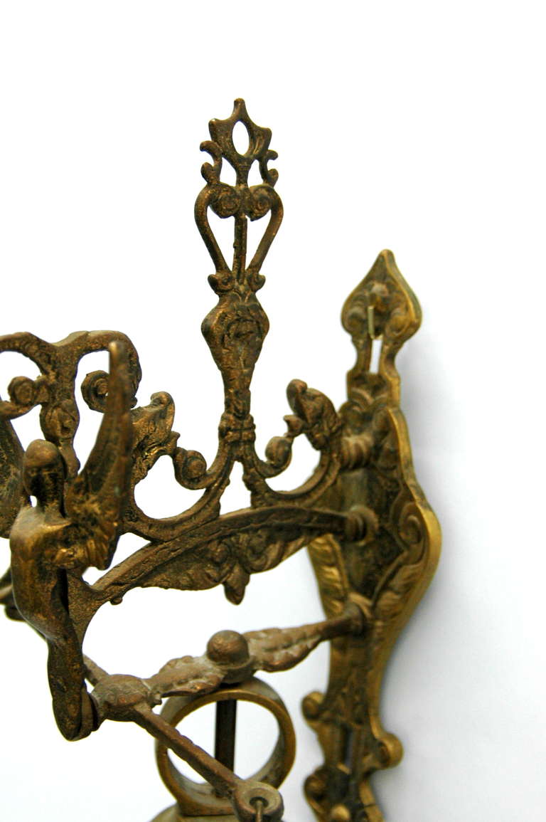An intricately carved brass doorbell with a pull chain and supporting hardware incorporating decoration with a sphinx.