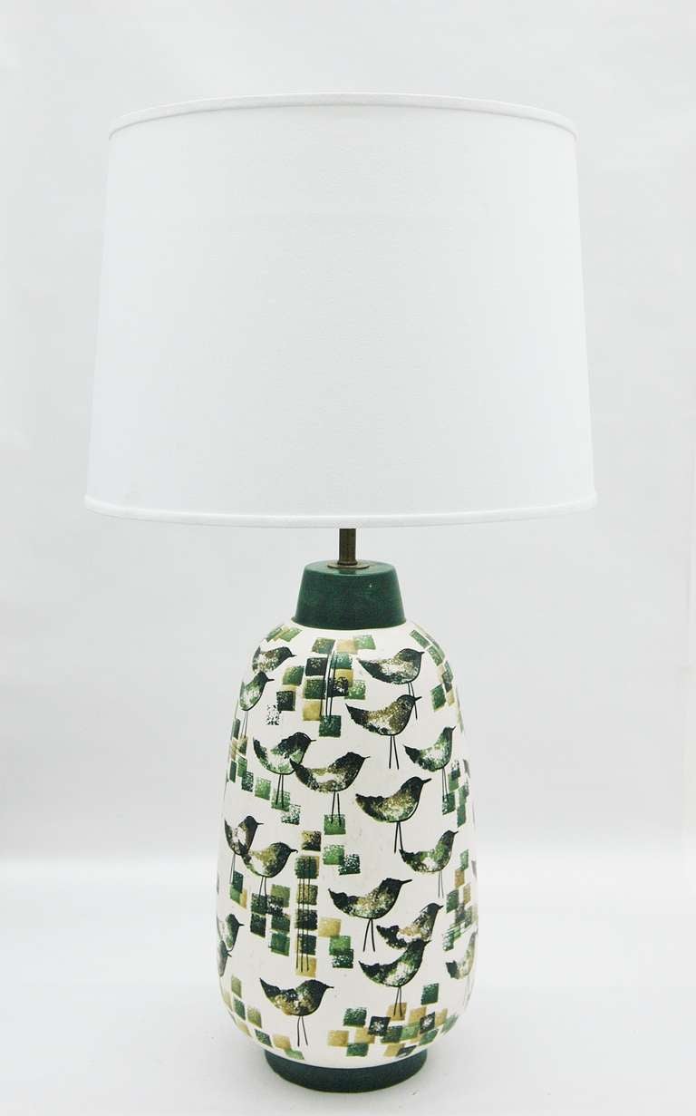 A large table lamp with a matching decorative box featuring a fun bird and square motif throughout the surface. Done in a forest green, yellow-green, mustard, and black with an off-white background. The base of the box is signed and marked 252 (see