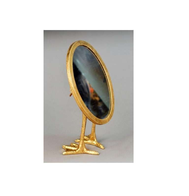 A fun oval table mirror on two bird's legs as supports. The use of birds feet as a base can be seen in Meret Oppenheim's Traccia table.