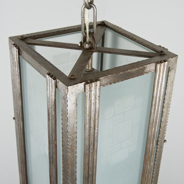 A petite square pendant light or lantern. The wrought iron frame with opaque (frosted) glass panels decorated in an etched geometric pattern.

The modernist Art Deco light in the manner of Paris-based designer M. Vasseur - a possibly attribution is