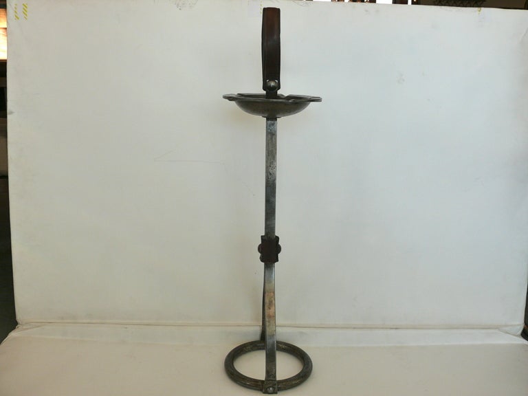 Great iron Adnet style ashtray stand with dark brown leather loop handle and leather strap detailing. Circular iron base and ashtray holder. Nice patina to original iron and leather.
Overall height with leather loop: 28