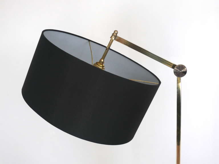 Stunning Jean Perzel brass crane floor lamp with cantilevered adjustable arm. Lamp rests on a square brass and black metal base. Simple yet sleek design. New black silk drum shade and newly rewired.