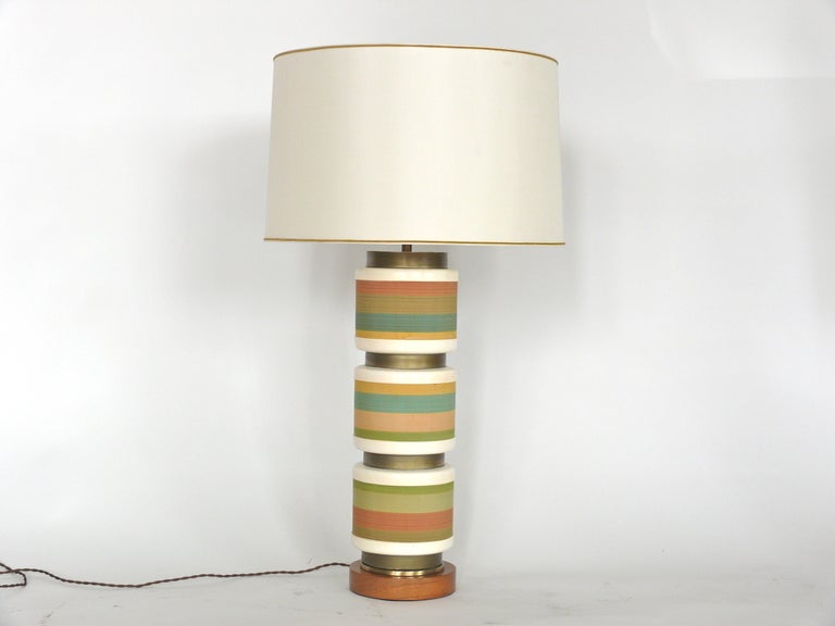 Large pair of ribbon stripe ceramic lamps that rest on a wood base with brass detail.  Great shades of green, orange, blue and yellow ribbon wrap around body of ceramic lamp. 
Height with lamp shade: 33