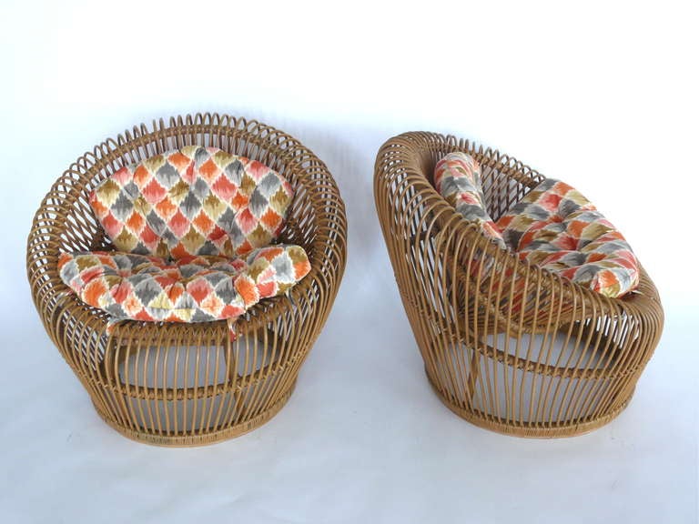 Beautiful pair of rattan chairs by Franco Albini for Vittorio Bonacina. Bucket shape with small scoop seats. Airy and aesthetically pleasing design. Great looping rattan detailing around edges. Newly upholstered cushions add great pop of color.