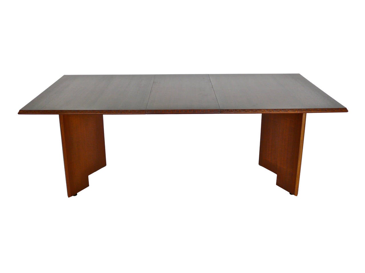 Handsome Frank Lloyd Wright dining table with two removable leaves manufactured by Heritage Henredon. Distinct carvings from the Taliesin Line which was named after Frank Lloyd Wright's home in Spring Green, Wisconsin. Mahogany table has been newly