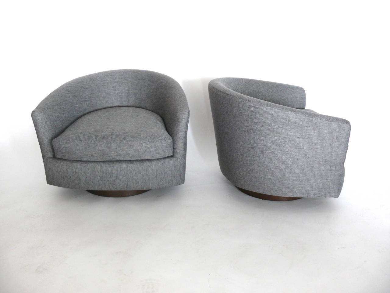 Handsome pair of grey linen bucket chairs in the style of Milo Baughman. Clean lines and newly reupholstered. Chairs sit upon dark walnut swivel bases. Very comfortable. Great for the home or office.