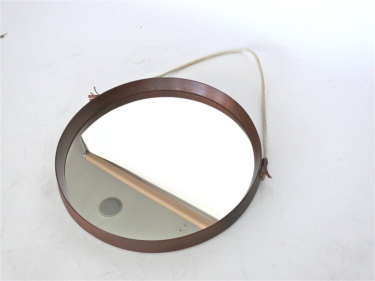 Round Danish mirror with teak frame. Mirror suspended by a twisted rope strap. Excellent vintage condition. Oval and octagonal teak mirrors also available.