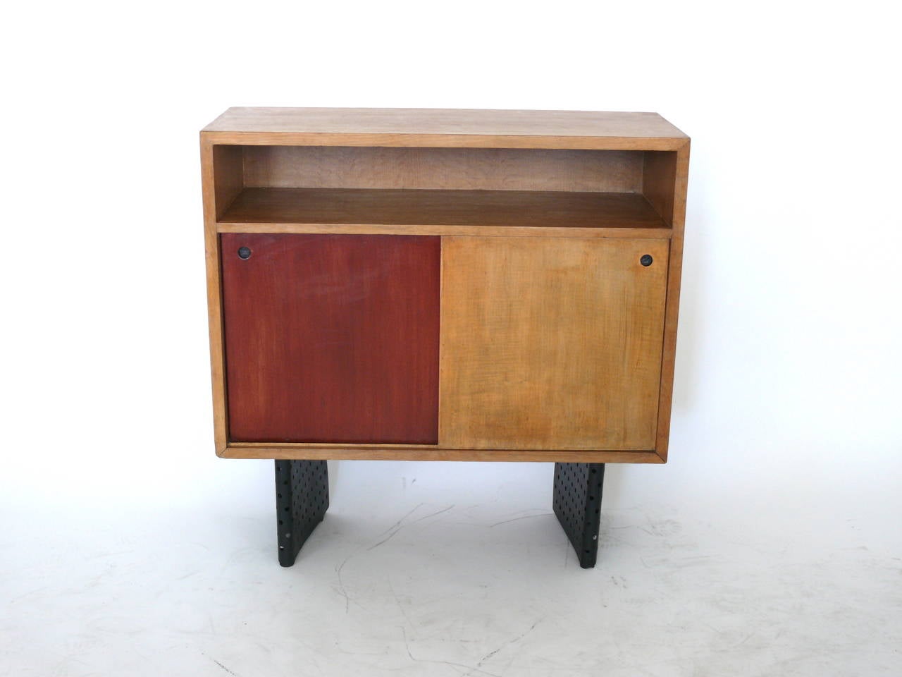 Gorgeous cabinet or bookcase designed by Escande, a student of Prouve. The cabinet is made of oak and rests on perforated black painted iron legs. Designed for the Anthony building in Strasbourg, France. Original wood finish with original muted red