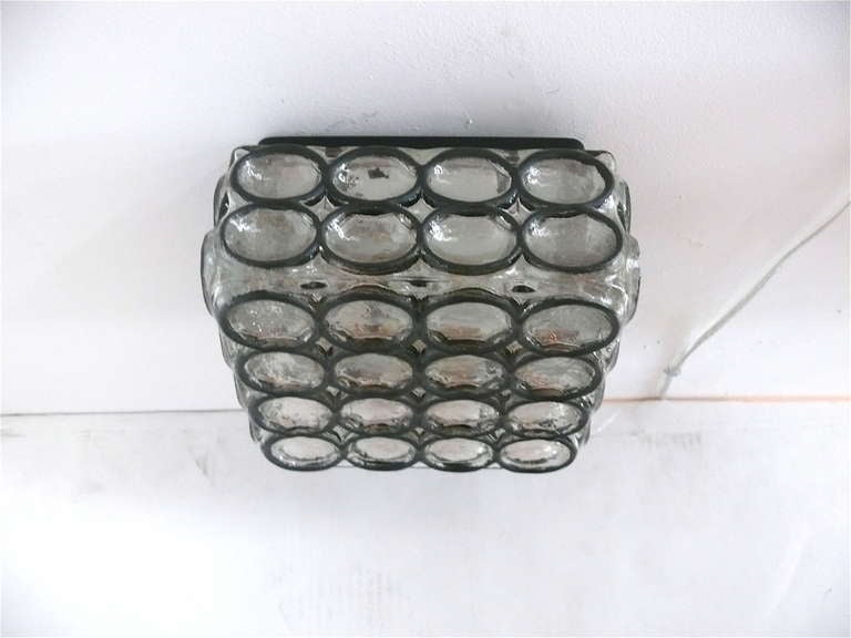 Kleine quadratische Unterputzdose aus Eisen und Glas. Schwarze Eisenkreise, eingelegt in dickes Limburg-Klarglas. Einzigartiges Design und schöne Beleuchtung. Neu verkabelt.
