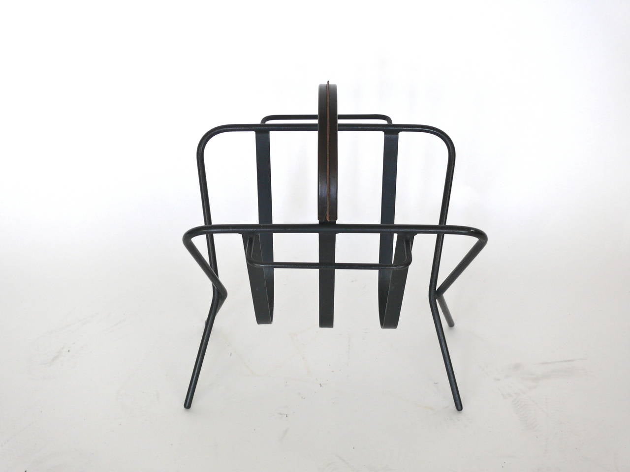 Large iron and leather magazine rack by Jacques Adnet. Heavy iron frame with brown leather wrapped handle. Great size. Excellent vintage condition.