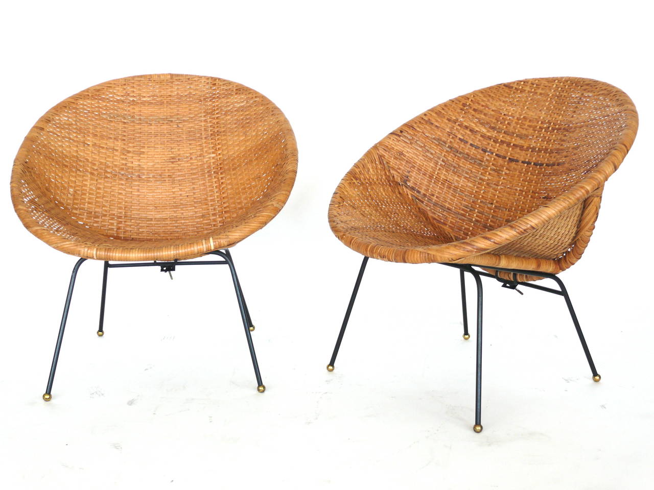 Handsome pair of of wicker and iron bucket chairs. Wicker in excellent condition. Iron legs have brass ball feet. Perfect for the home or covered outdoor patio.
