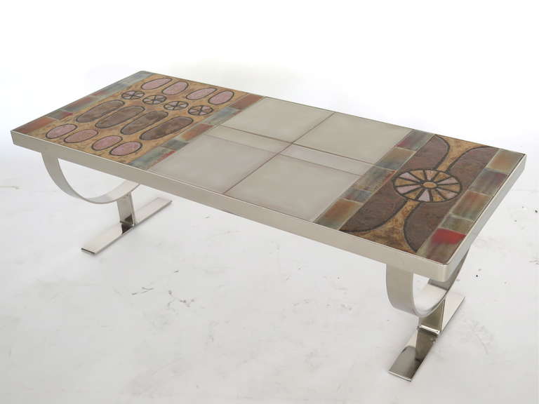 Fantastic tile table by Roger Capron. Beautiful white square tiles feature geometric and whimsical bright designs on surface. Low profile with angled stainless steel legs. Great scale and presence!