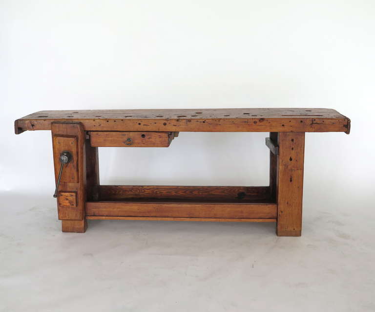 Spectacular French industrial workbench. Incredible wear and patina throughout work surface including cut outs, imprints and grates. Table includes an original vise and pull out storage drawer. Would make be a perfect statement piece in any entry or