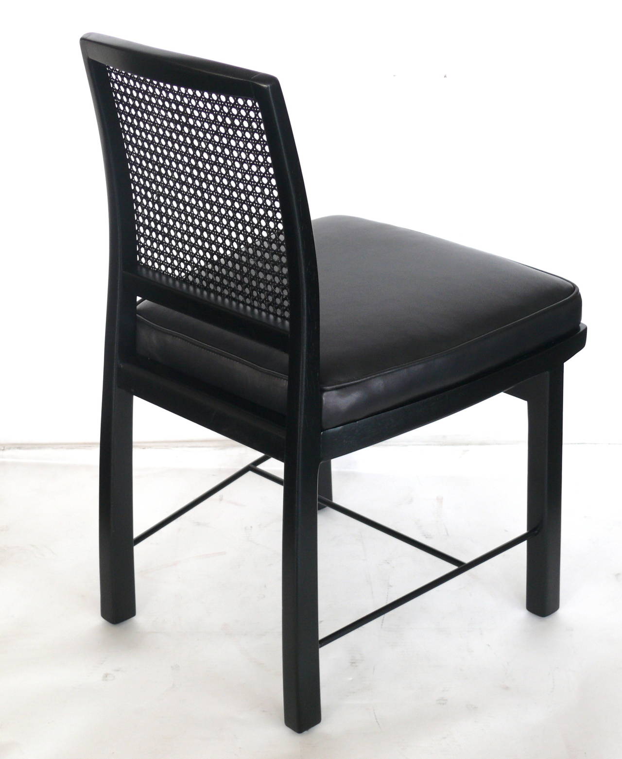 Handsome set of Edward Wormley for Dunbar side chairs. Jet black chair frames complimented by caned back detail. Seats have been newly upholstered in a black lamb skin. Two chairs available. Priced individually.
