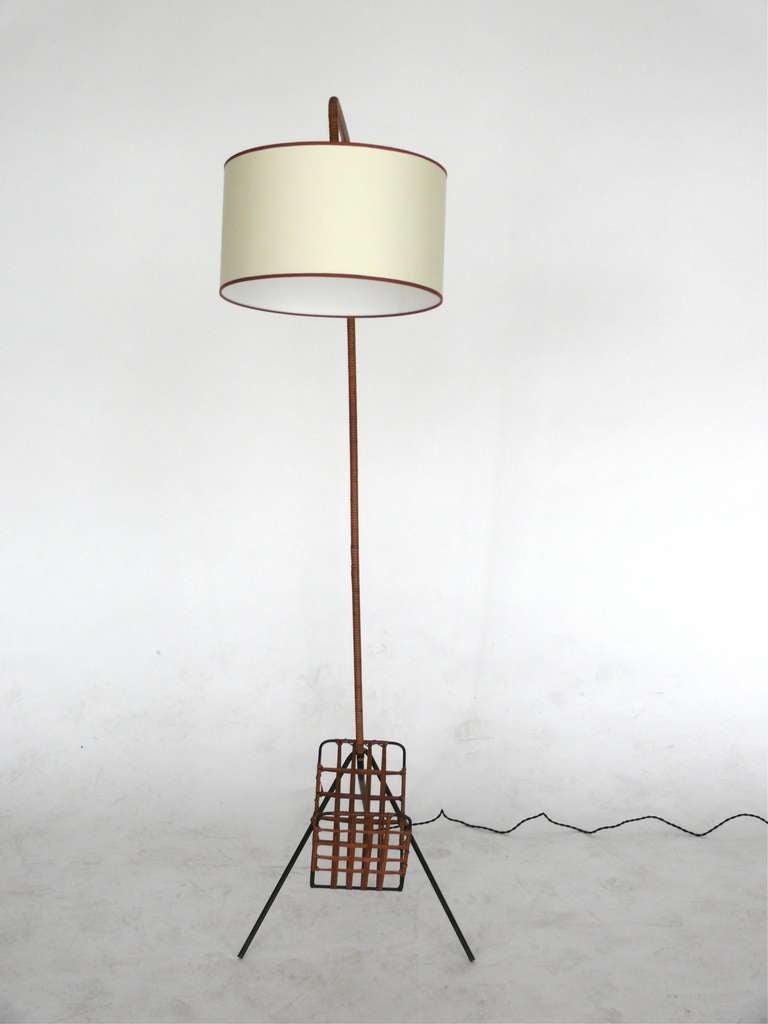 Incredible French floor lamp with arched neck and iron tripod base. Woven rattan magazine rack attached to bottom of fixture. Simple design with great mix of texture. Newly re-wired with original shade.