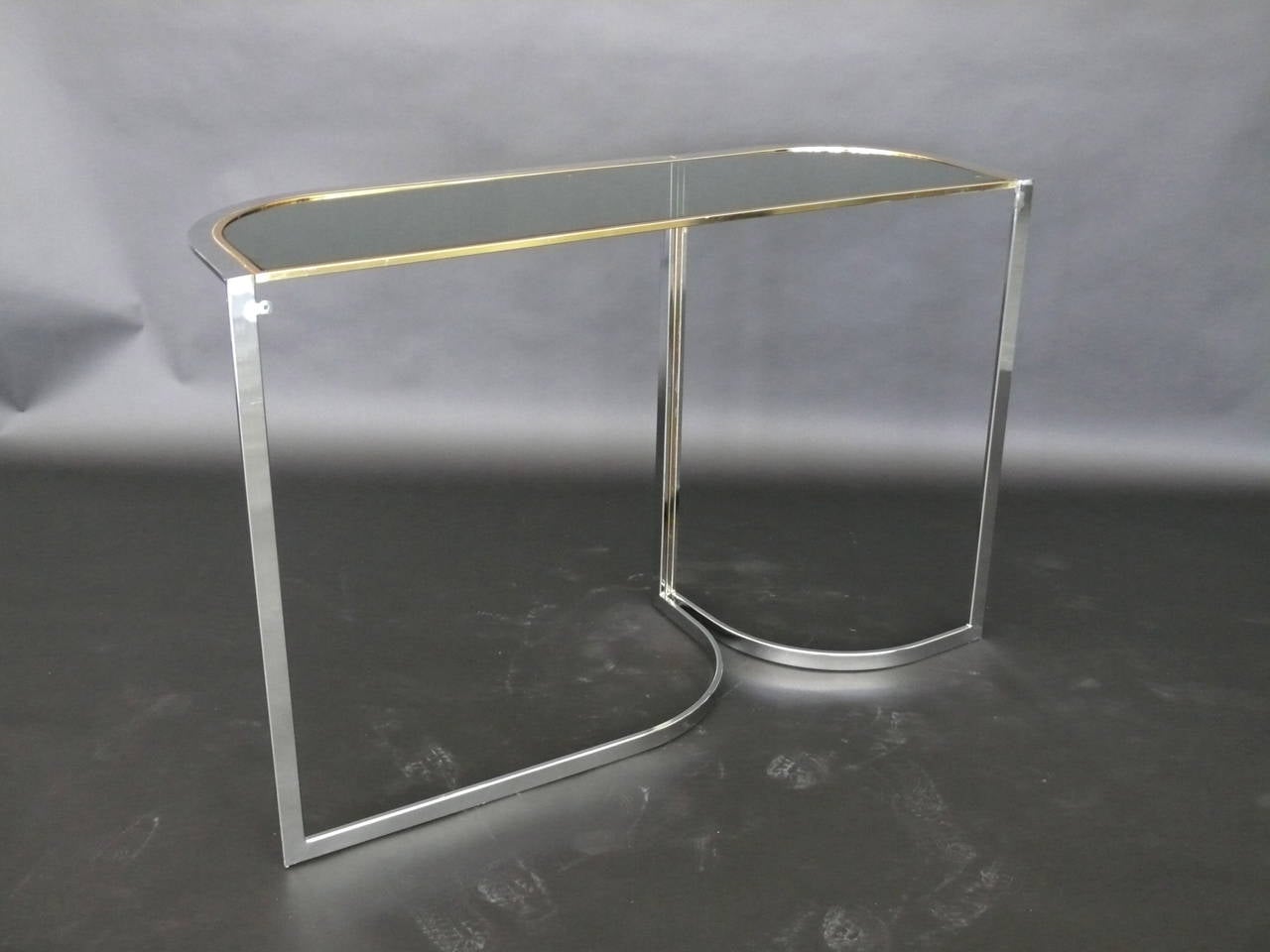 Sleek Italian console table. Chrome base has great lines and form. Original black inlaid glass with brass trim. Table is in excellent vintage condition.