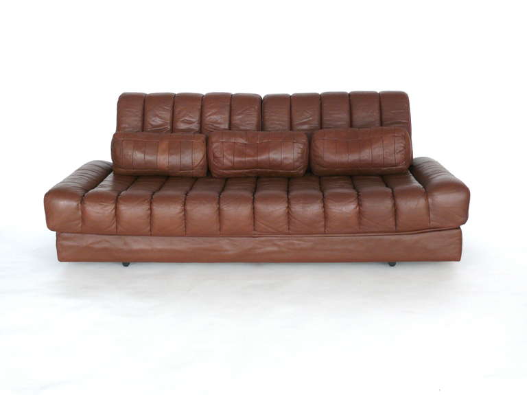 Incredible piped leather sofa bed by De Sede. Polished chrome tubular frame exposed in back of piece. Sofa transforms into a double mattress or also functions as a chaise lounge. Fantastic patina and wear throughout leather. Includes two large