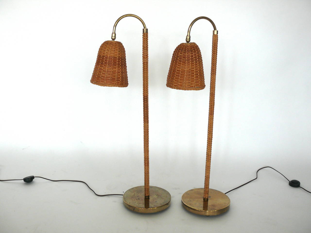 Fantastic pair of Rattan, wicker and brass floor lamps. Lamps are height adjustable with a pivoting shade. Neck of floor lamp is rattan with a brass base. Excellent vintage condition. Newly rewired. Illuminates beautifully.