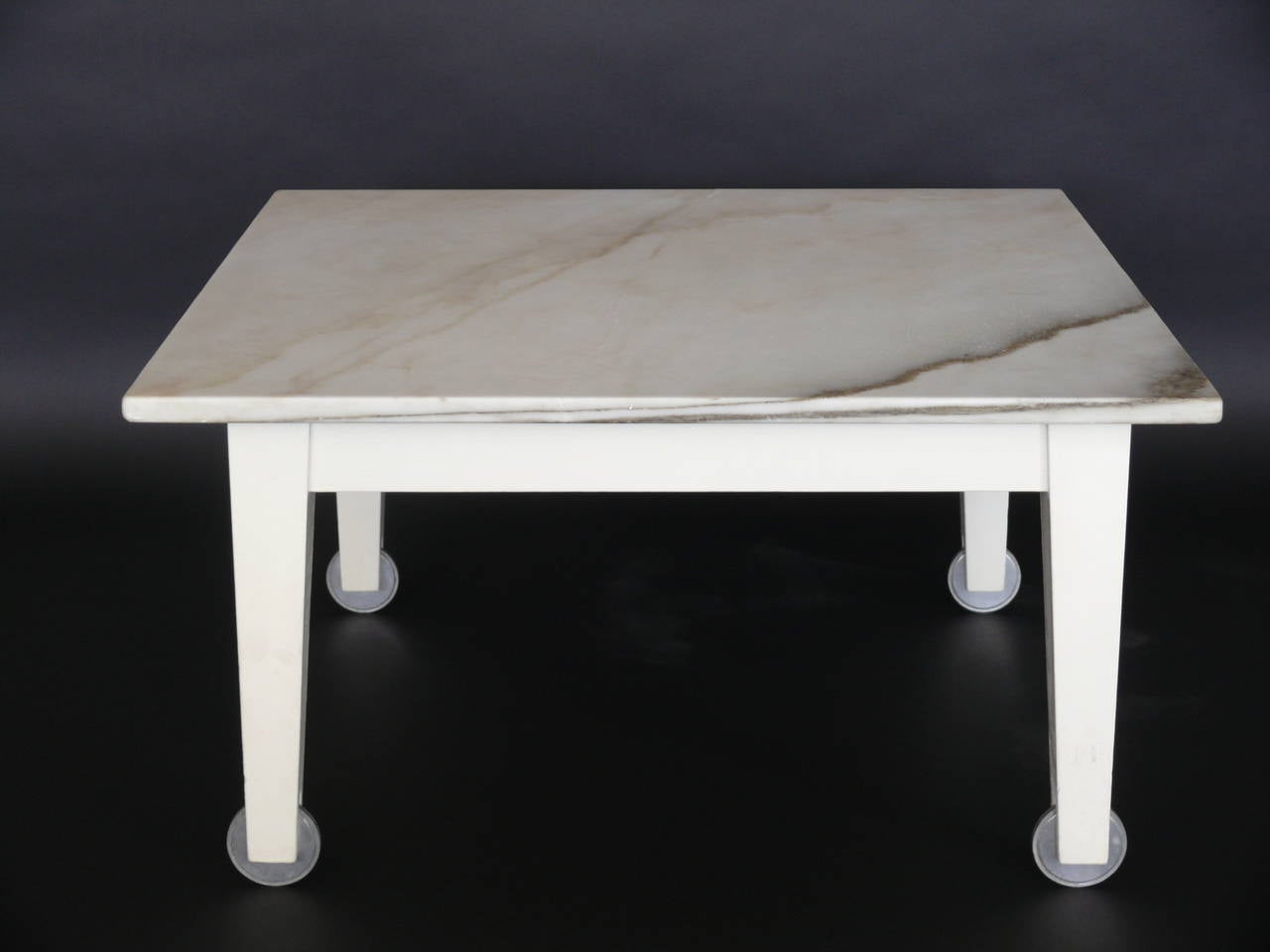 Coffee table designed by Phillipe Starck for the Delano Hotel in 1980. Wood base with inset wheels and Carrara marble top. Vintage condition with repaired crack in marble. Other matching items from the Delano Hotel also available.