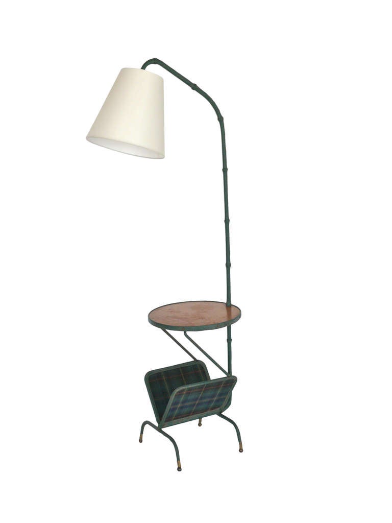 Gorgeous hunter green leather floor lamp by Jacques Adnet. Arched neck with signature stitching throughout. Oak table with green and red plaid magazine rack attached to bottom of fixture.  Newly re-wired with new silk shade.