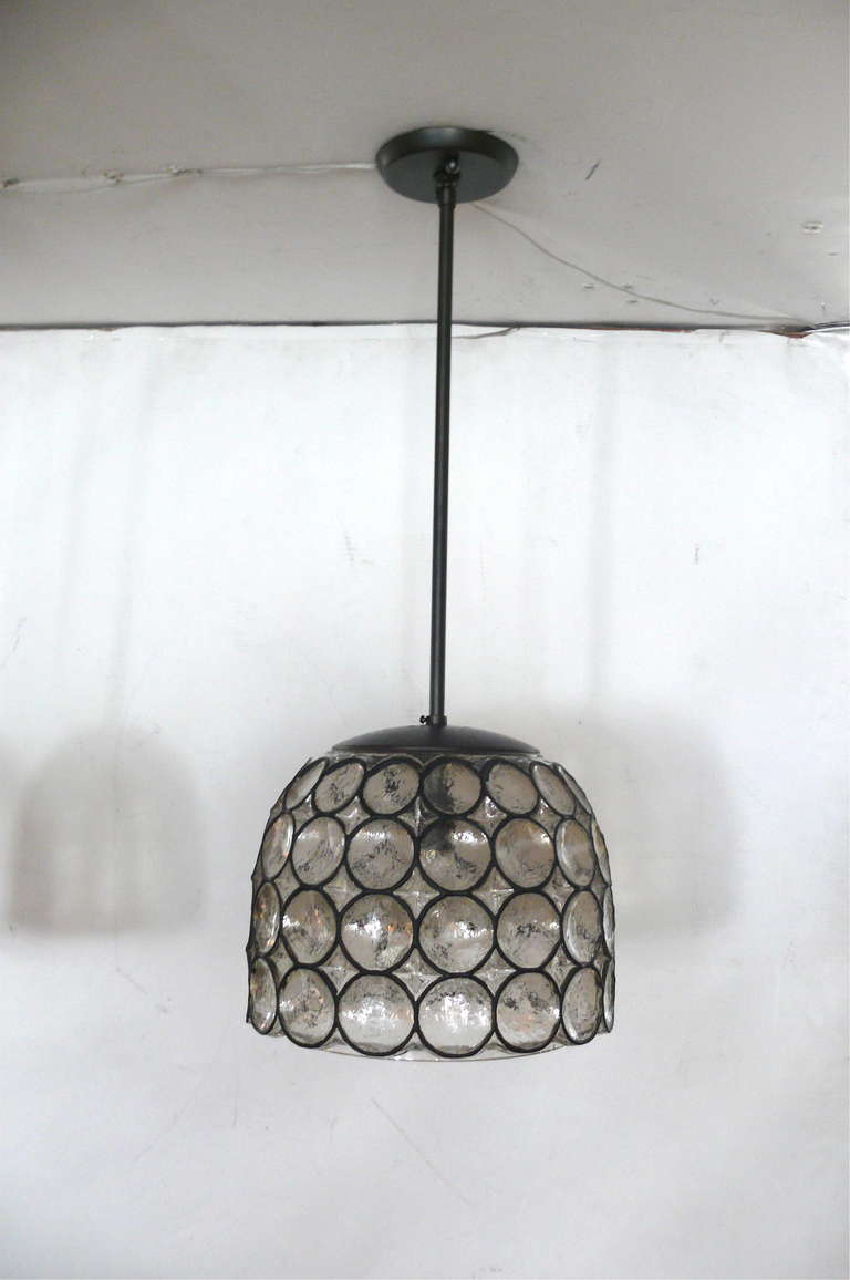 Beautiful iron and glass bell-shaped pendant, with black iron circles inlaid in thick clear Austrian glass. Oil rubbed bronze stem and canopy. Unique design that illuminates beautifully. Newly rewired.

Multiple Available. 