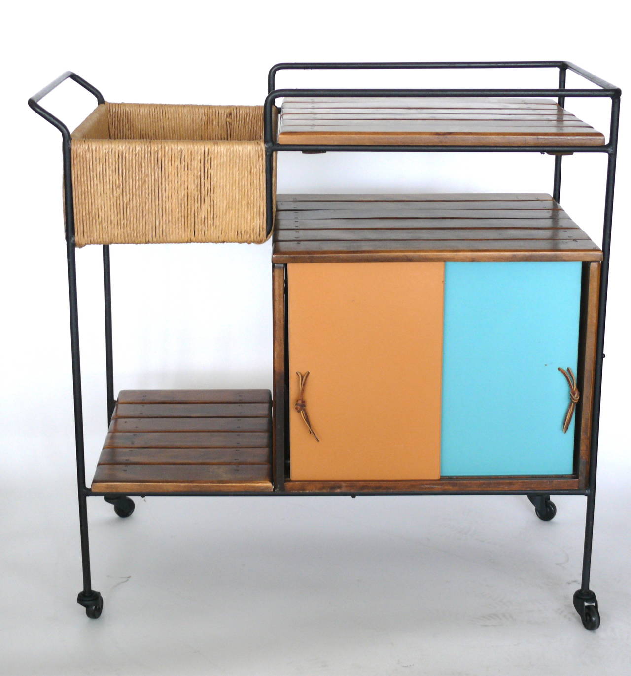 Whimsical bar cart by Arthur Umanoff on black casters. Iron framed cart features slatted wood, multiple shelves and an enclosed cabinet. Great colors and in excellent vintage condition.