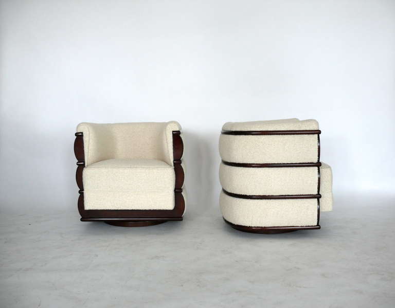 Fantastic pair of swivel chairs with stained walnut wood detail on back. Newly reupholstered in a creamy white wool boucle fabric. Extremely comfortable with unique design.